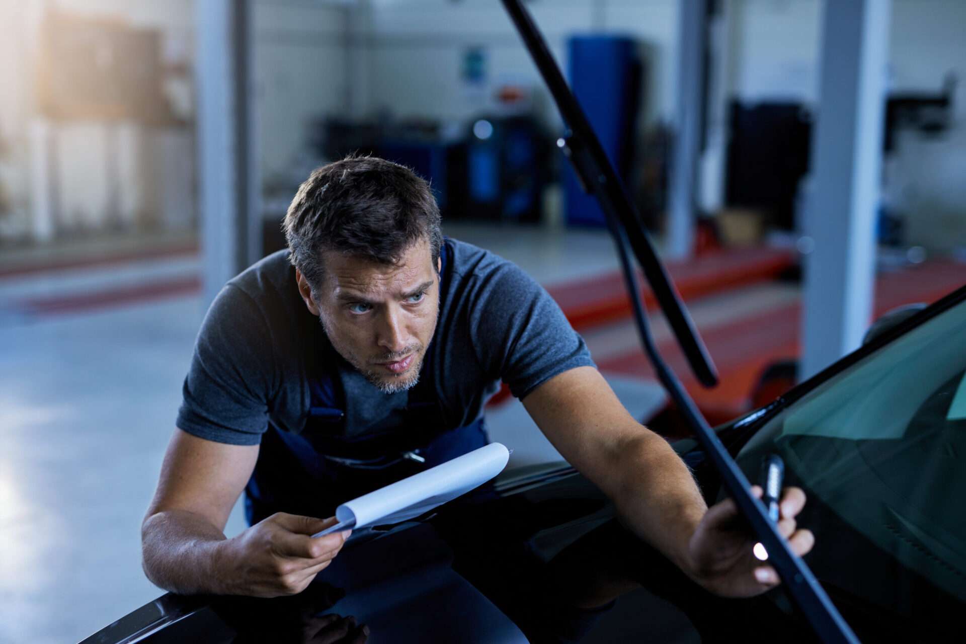 auto repairman examining a car while working at workshop.